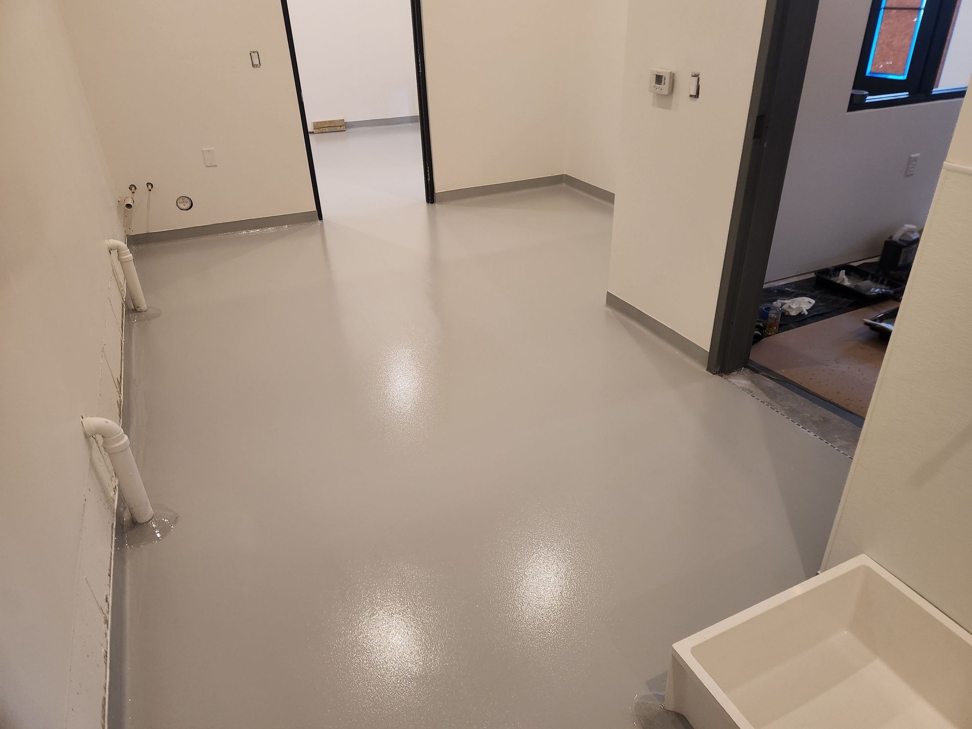 A room with a gray floor and a sink in it.