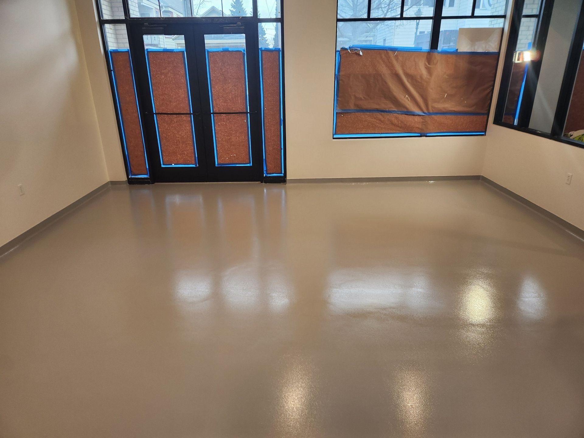 A large empty room with a concrete floor and a door.