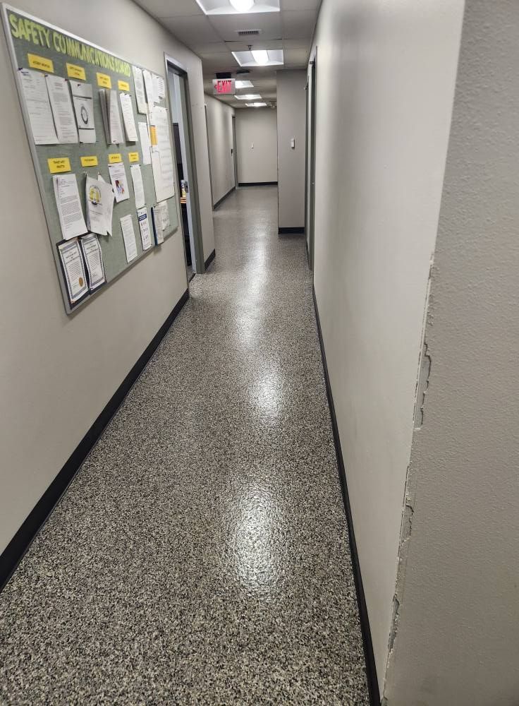 A long hallway with a bulletin board on the wall.