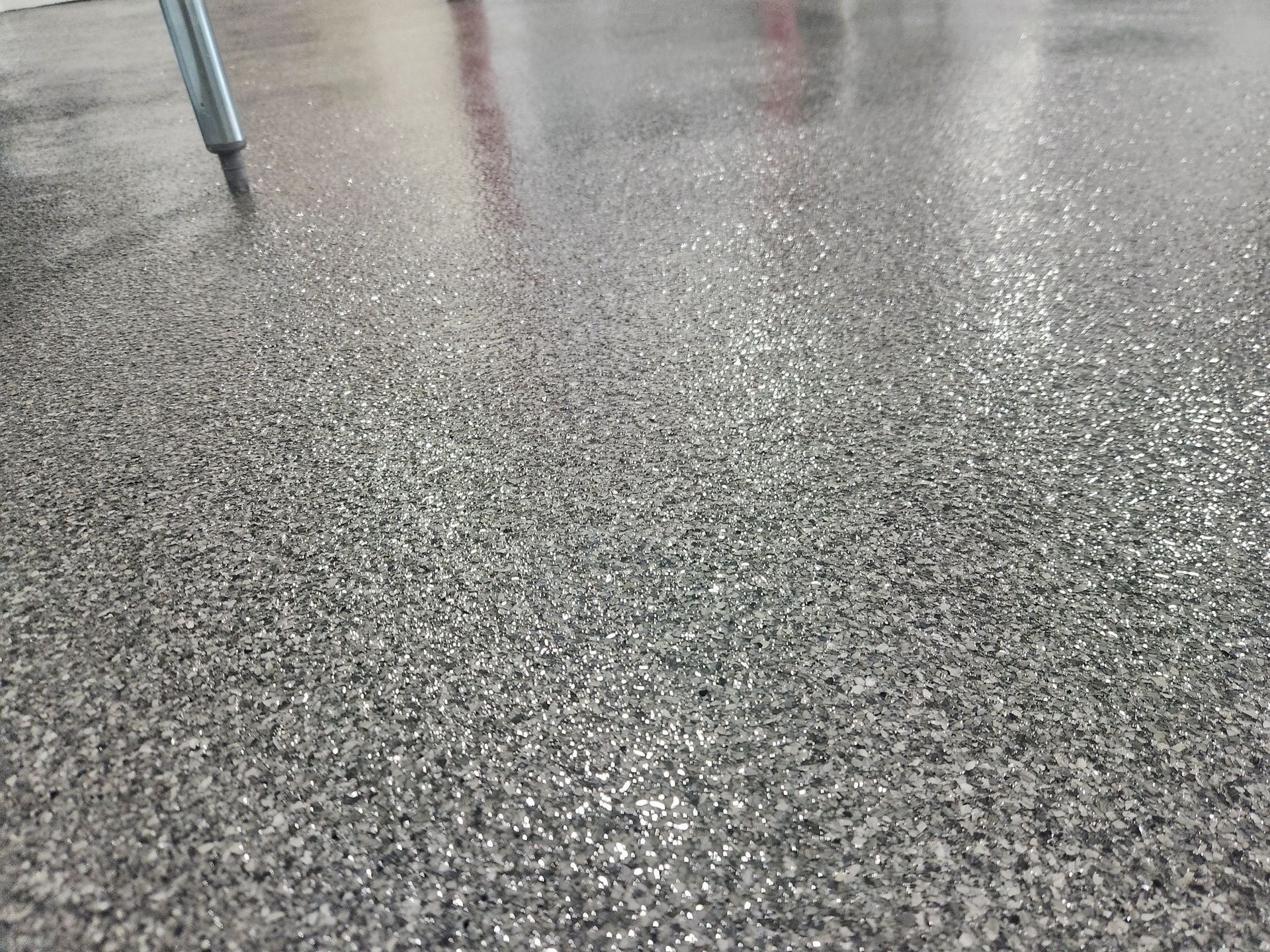 A close up of a gray floor with a chair in the background.
