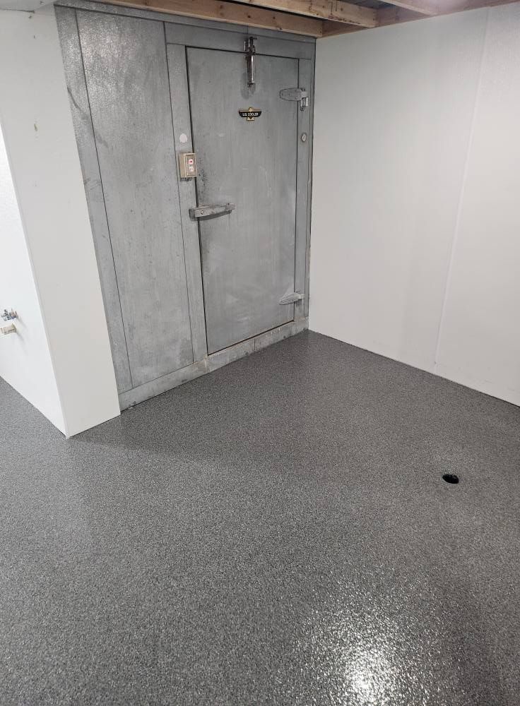 A room with a metal door and a gray floor.