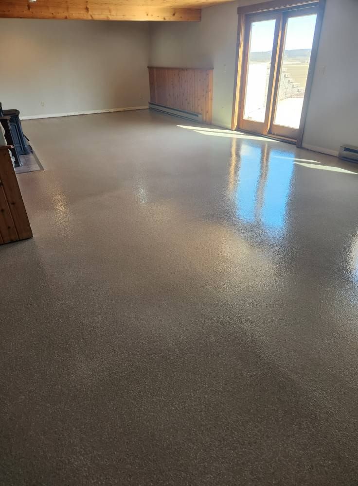 A large empty room with a concrete floor and sliding glass doors.