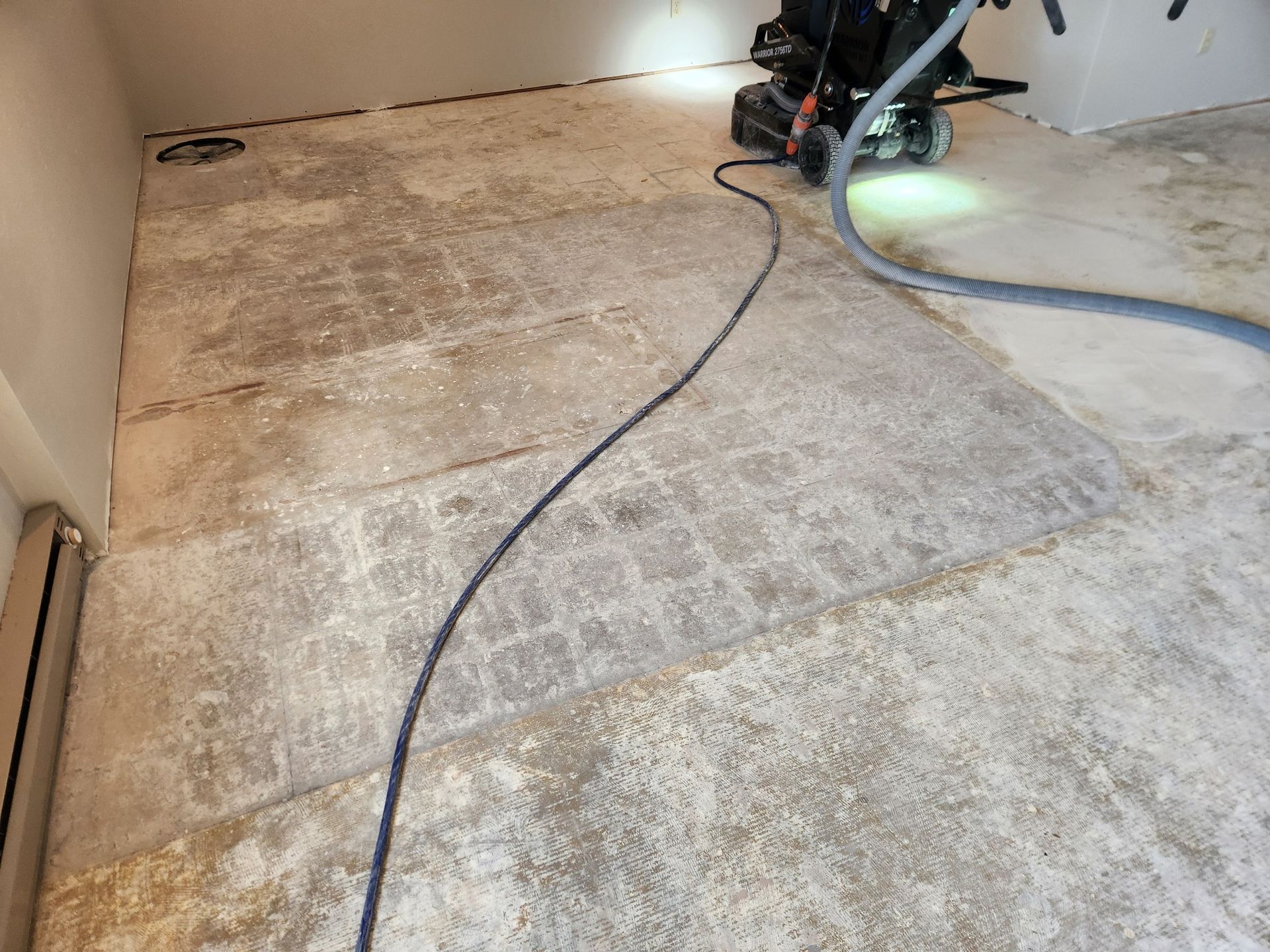 A vacuum cleaner is being used to clean a concrete floor.