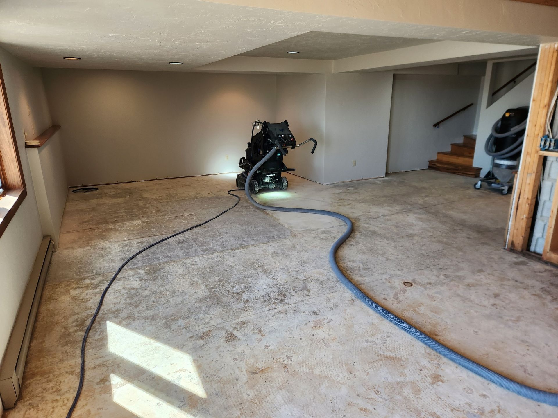 A room with a vacuum cleaner on the floor and stairs in the background.