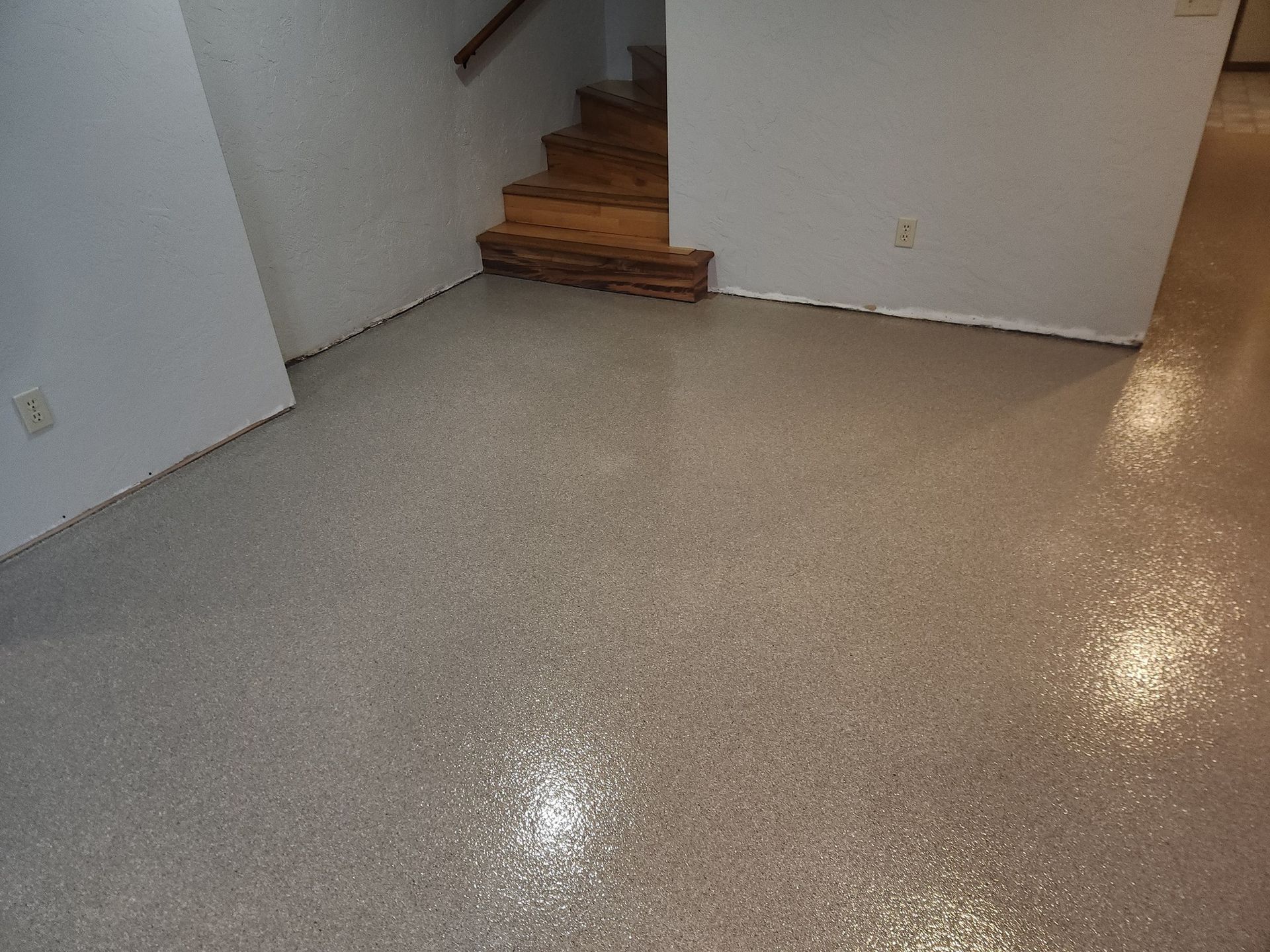 A room with a staircase and a shiny floor.