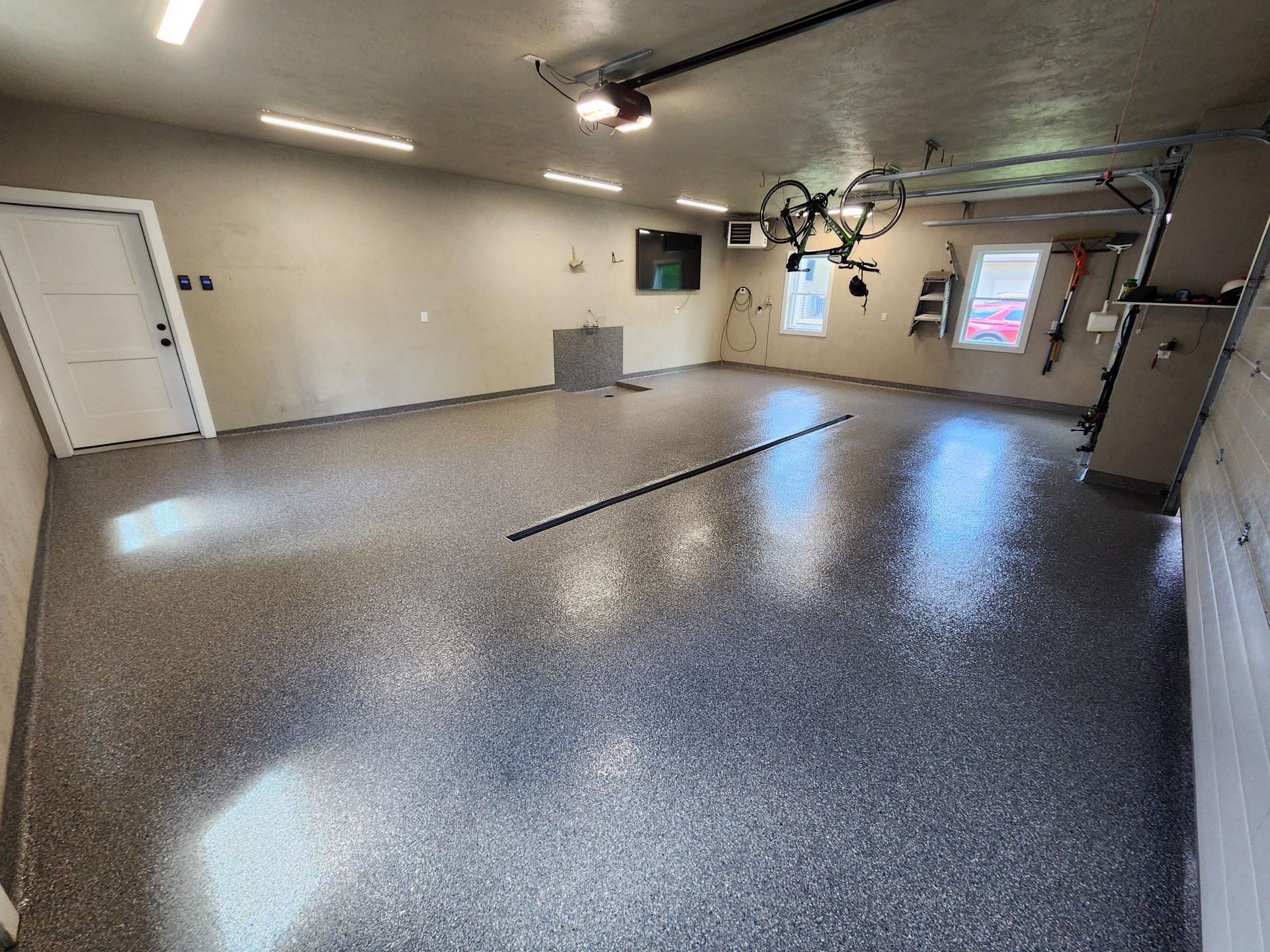 A large garage with a bicycle hanging from the ceiling.