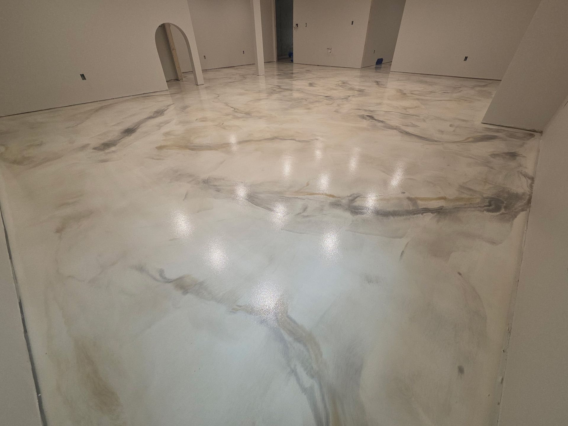 Marble floor with wet, cloudy reflections in an unfinished room with white walls