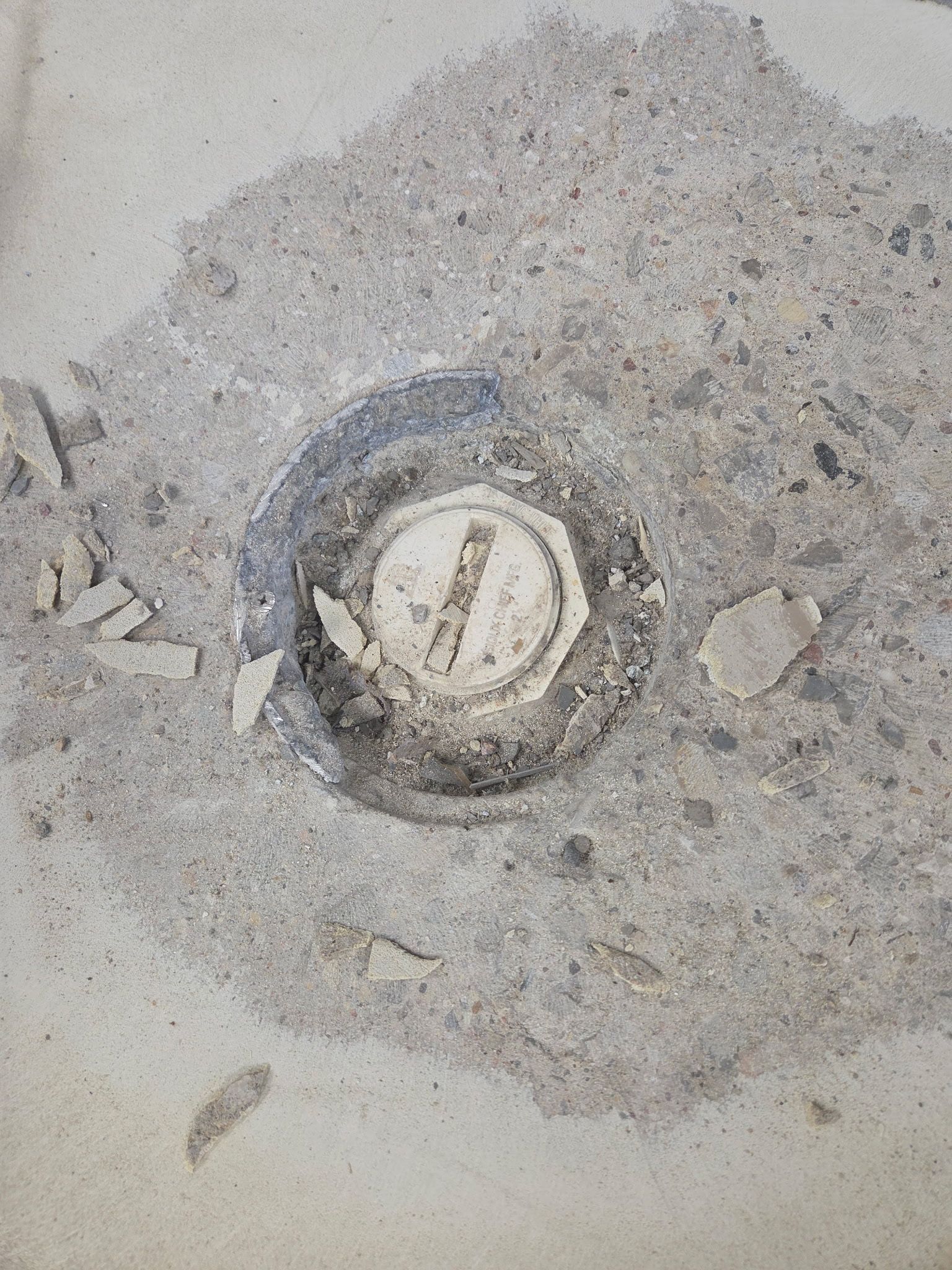 Close-up of a dusty circular drain or pipe opening in concrete.