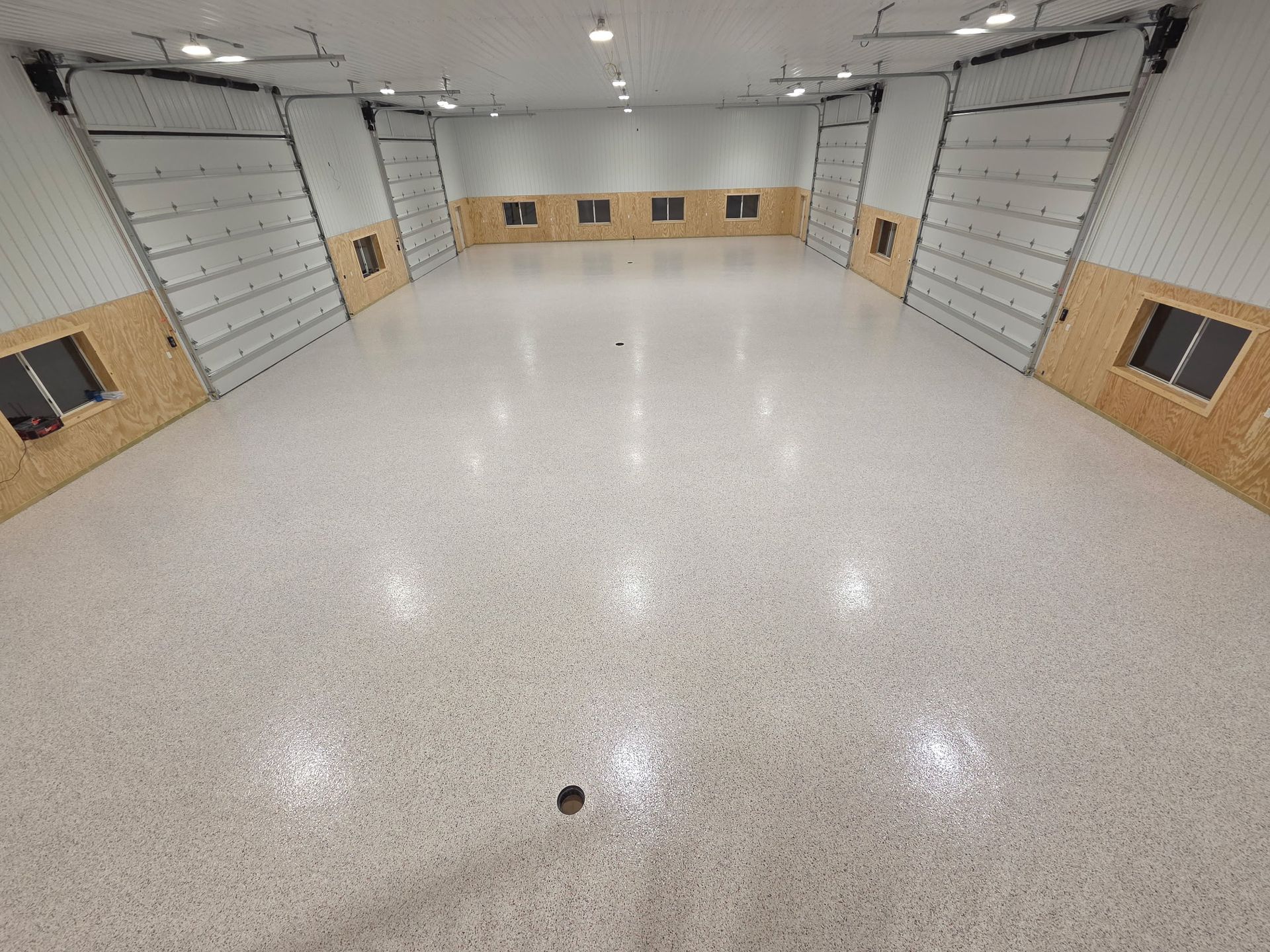 Empty indoor room with glossy white floor, wood-paneled walls, and large gray side doors.