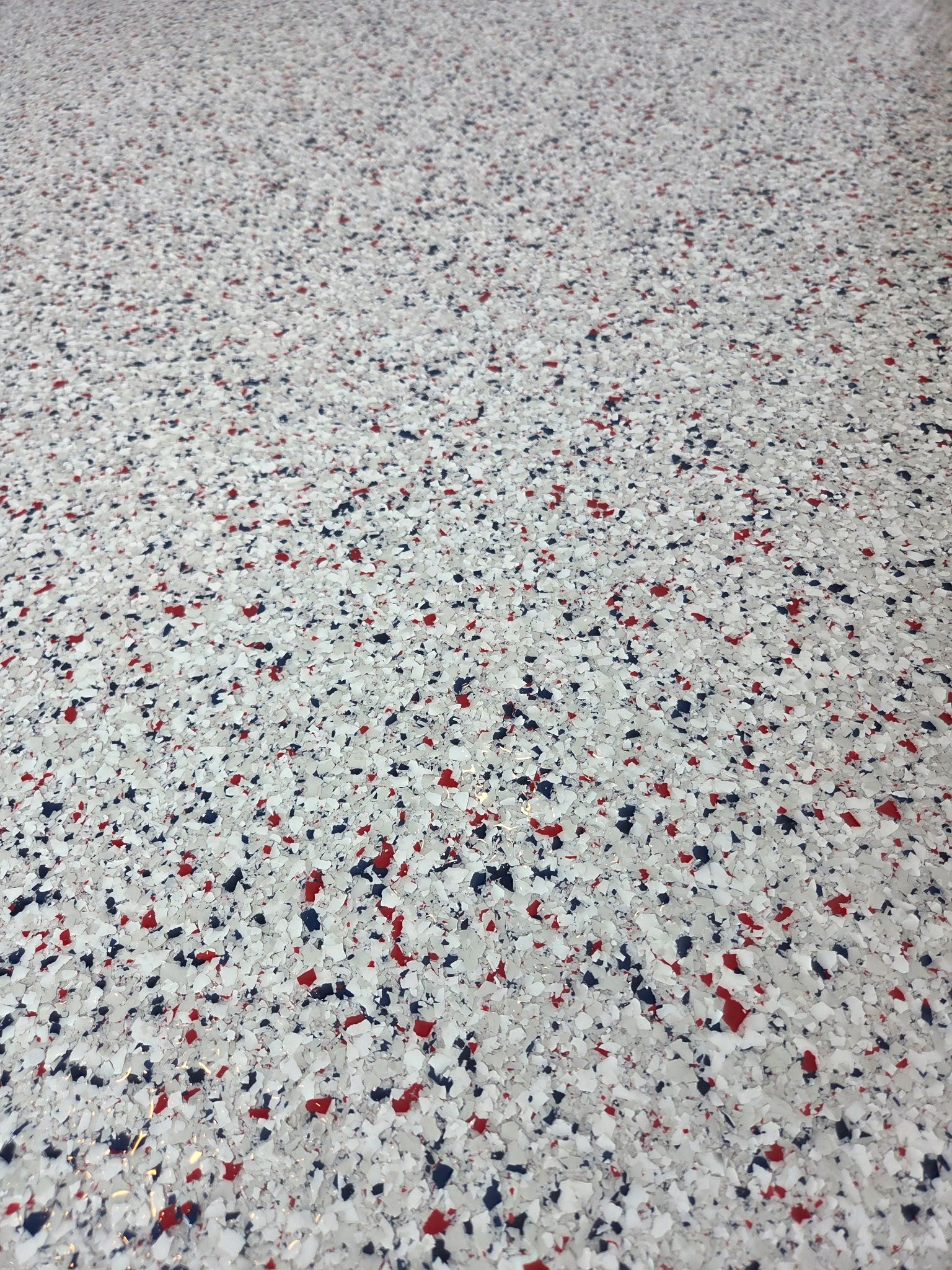 Close-up of speckled gray terrazzo flooring with scattered red and black chips.