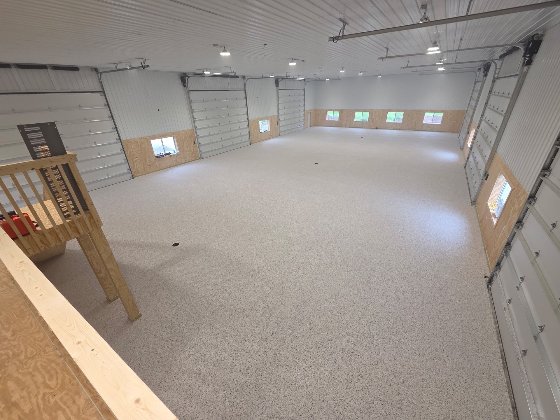 Empty unfinished room with white walls, beige carpet, and small windows along the sides