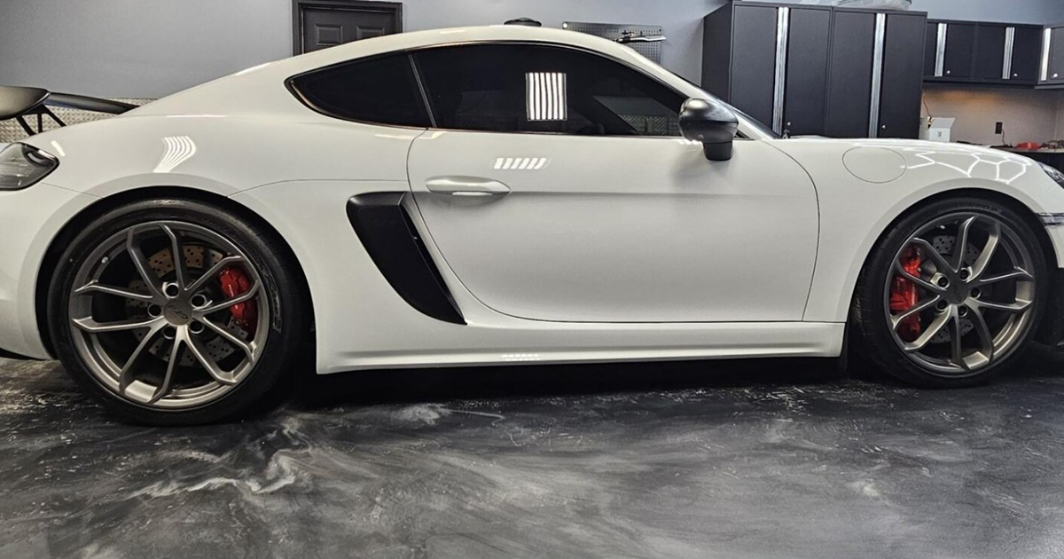 A white sports car is parked in a garage.