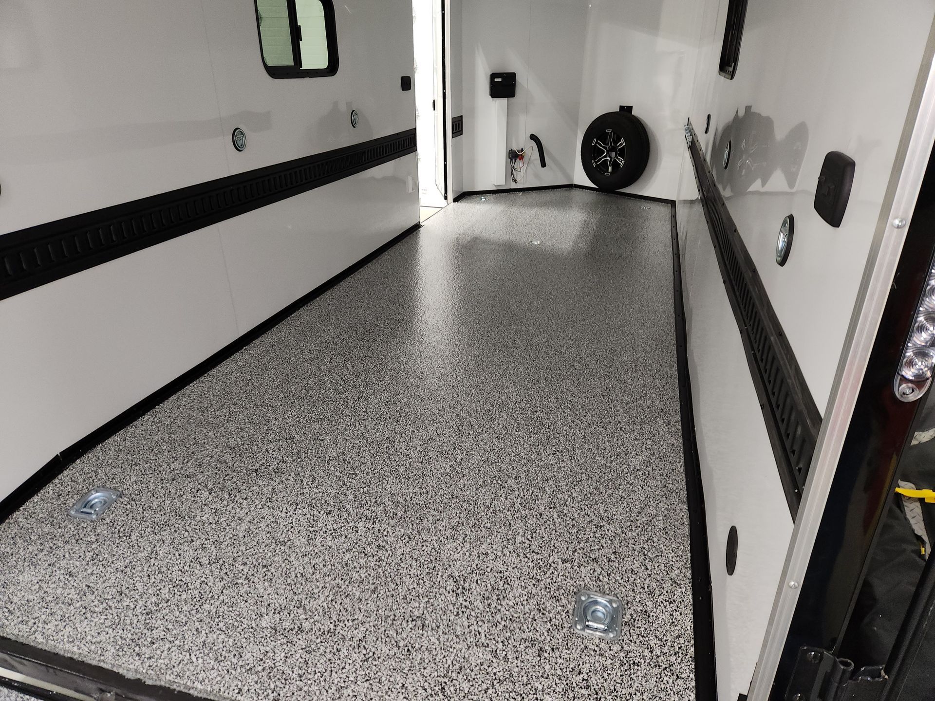 The inside of a trailer with a tire on the side of it.