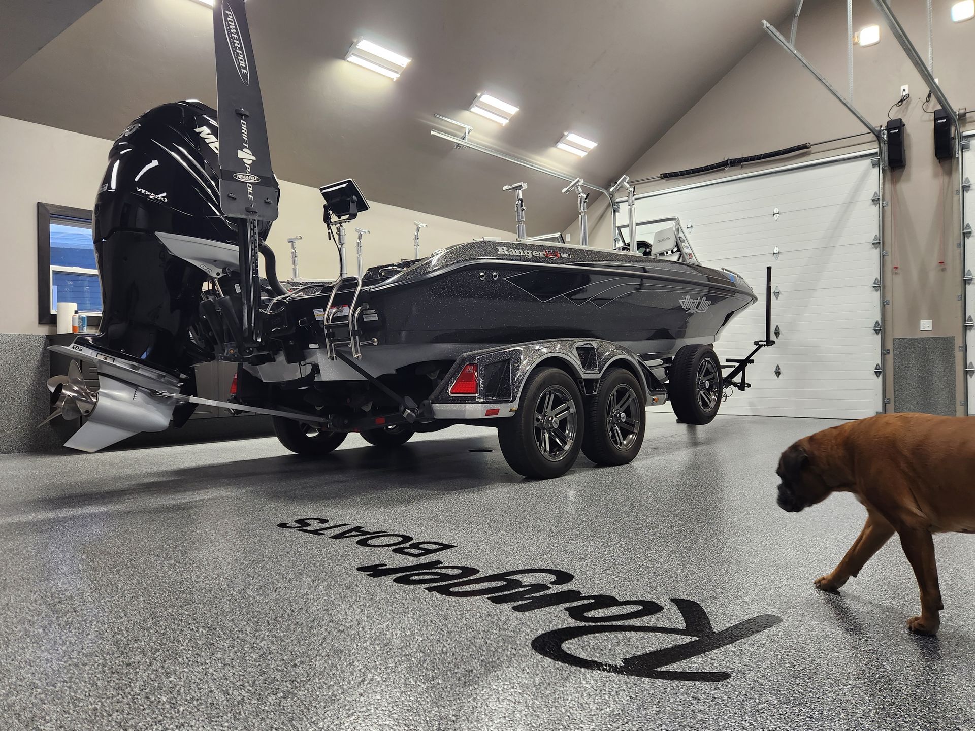 A dog is standing next to a boat in a garage.