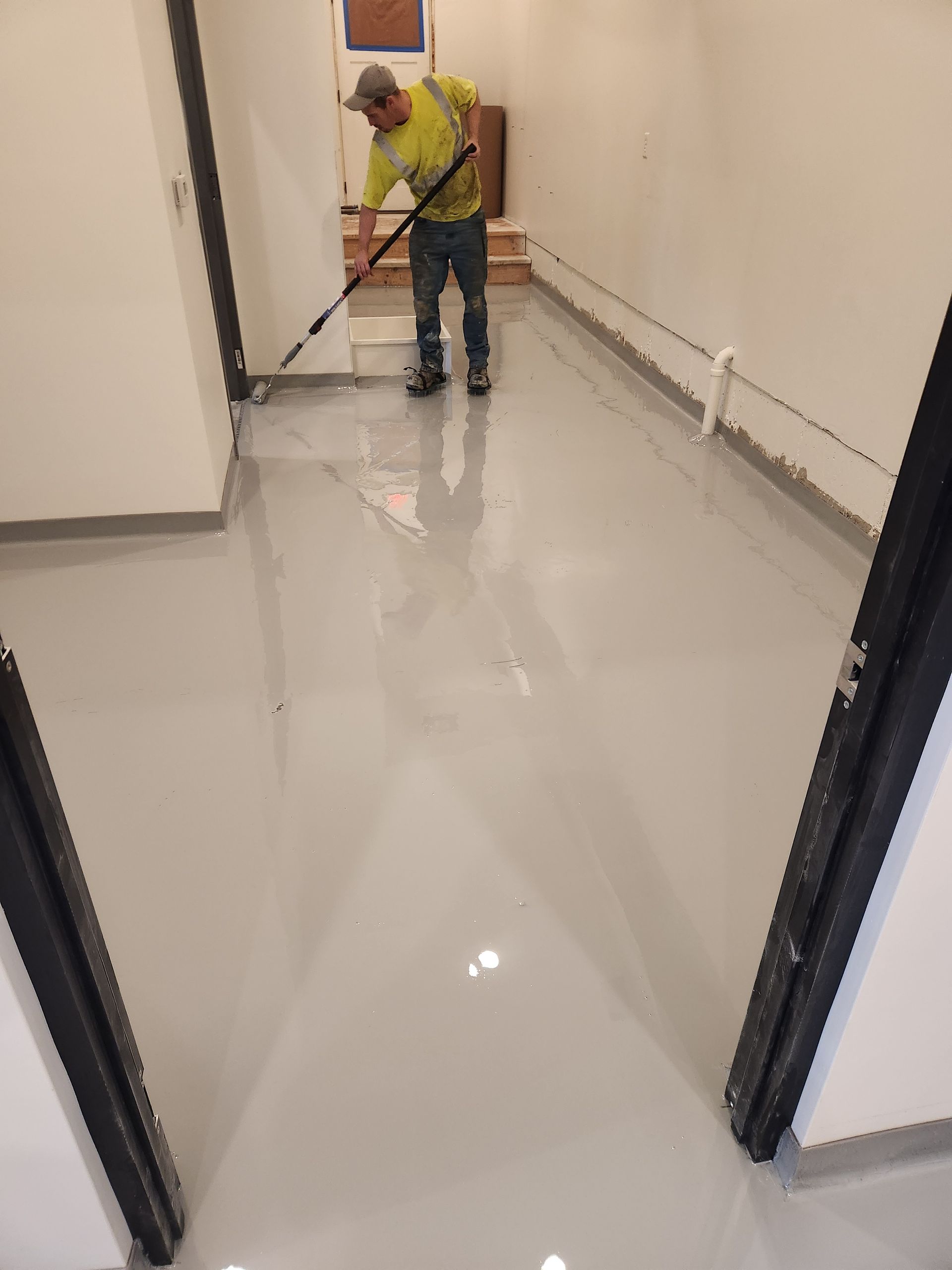 A man is painting a floor with a broom.