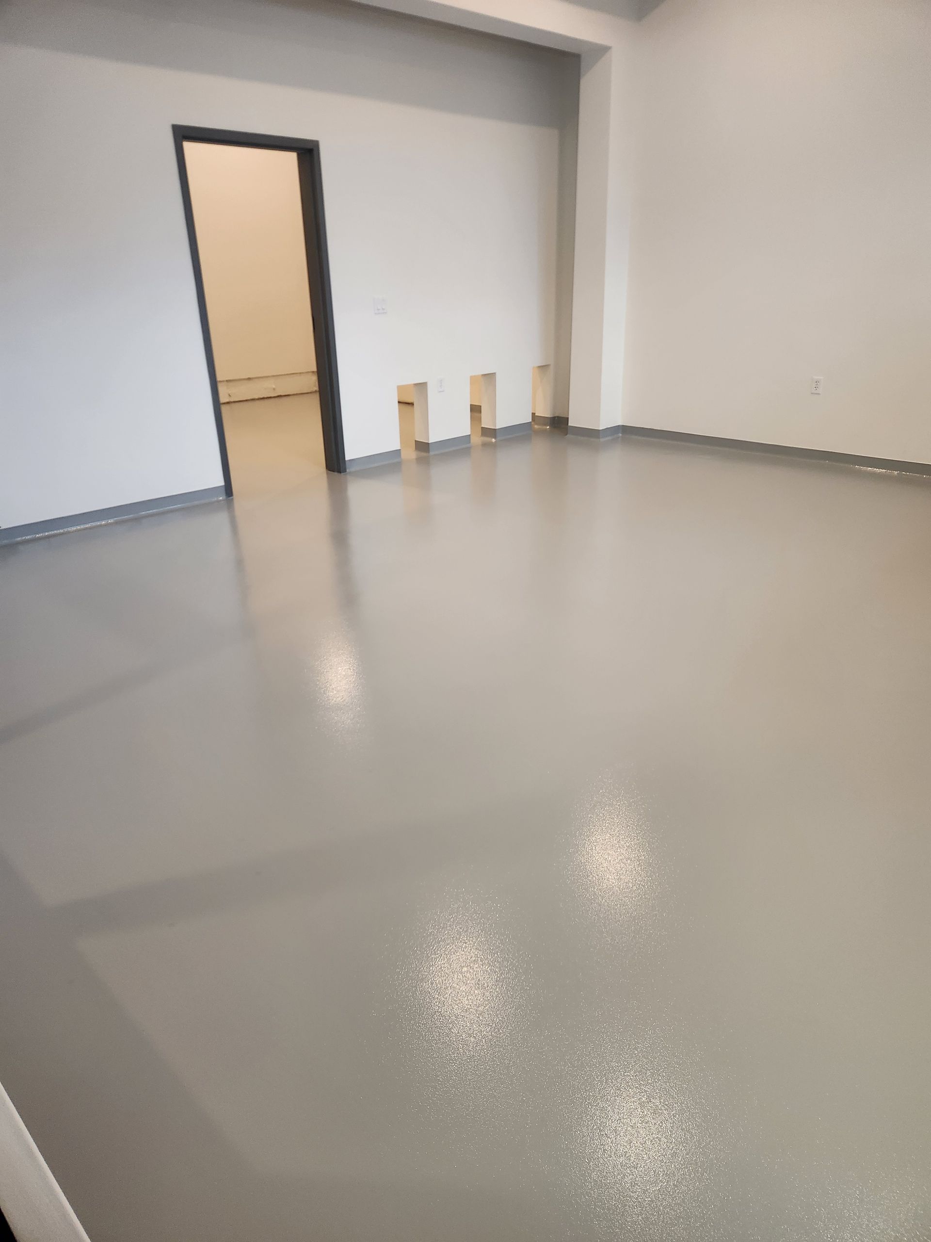 A large empty room with a gray floor and white walls.