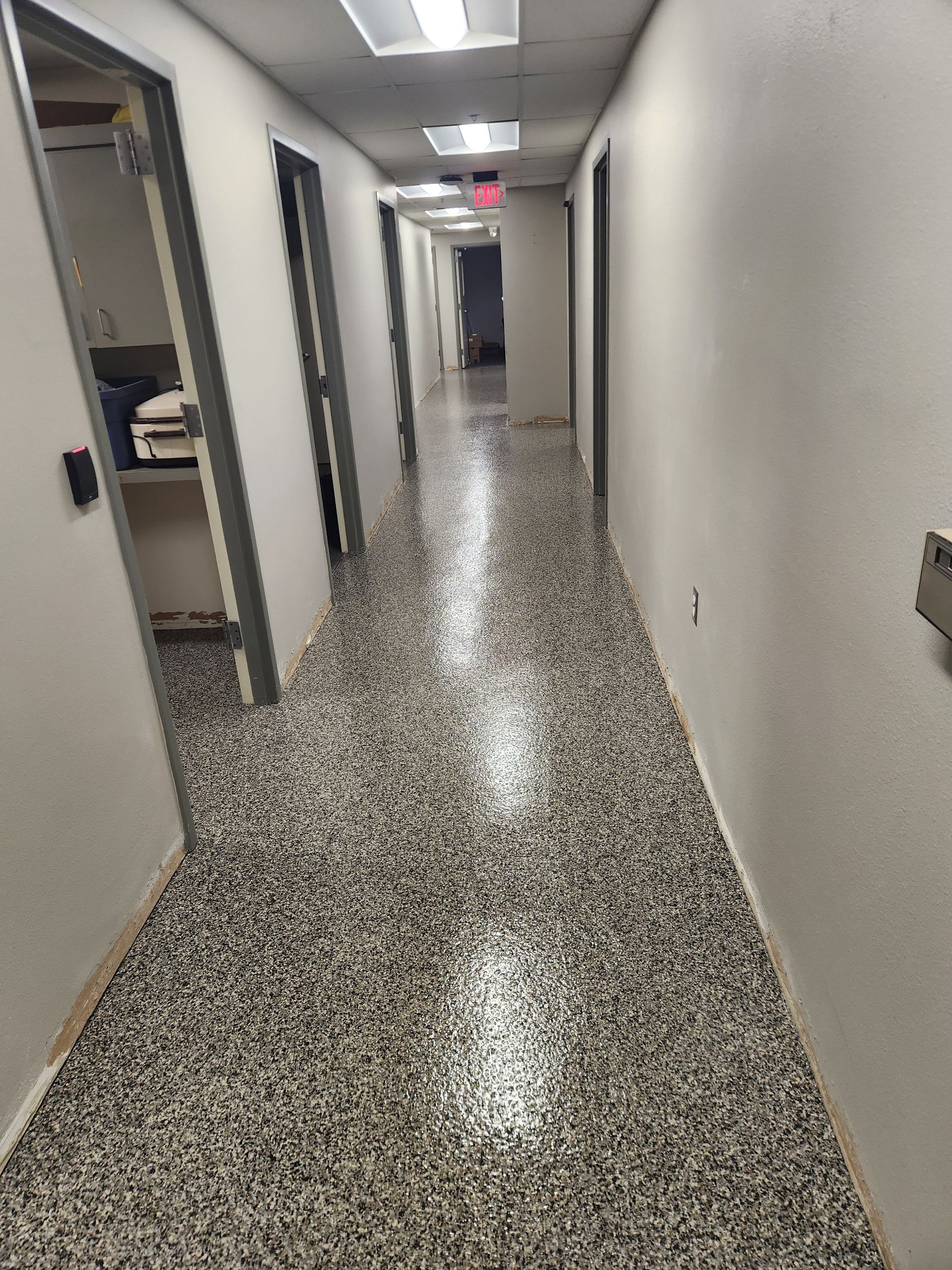 A long hallway with a gray floor and white walls.
