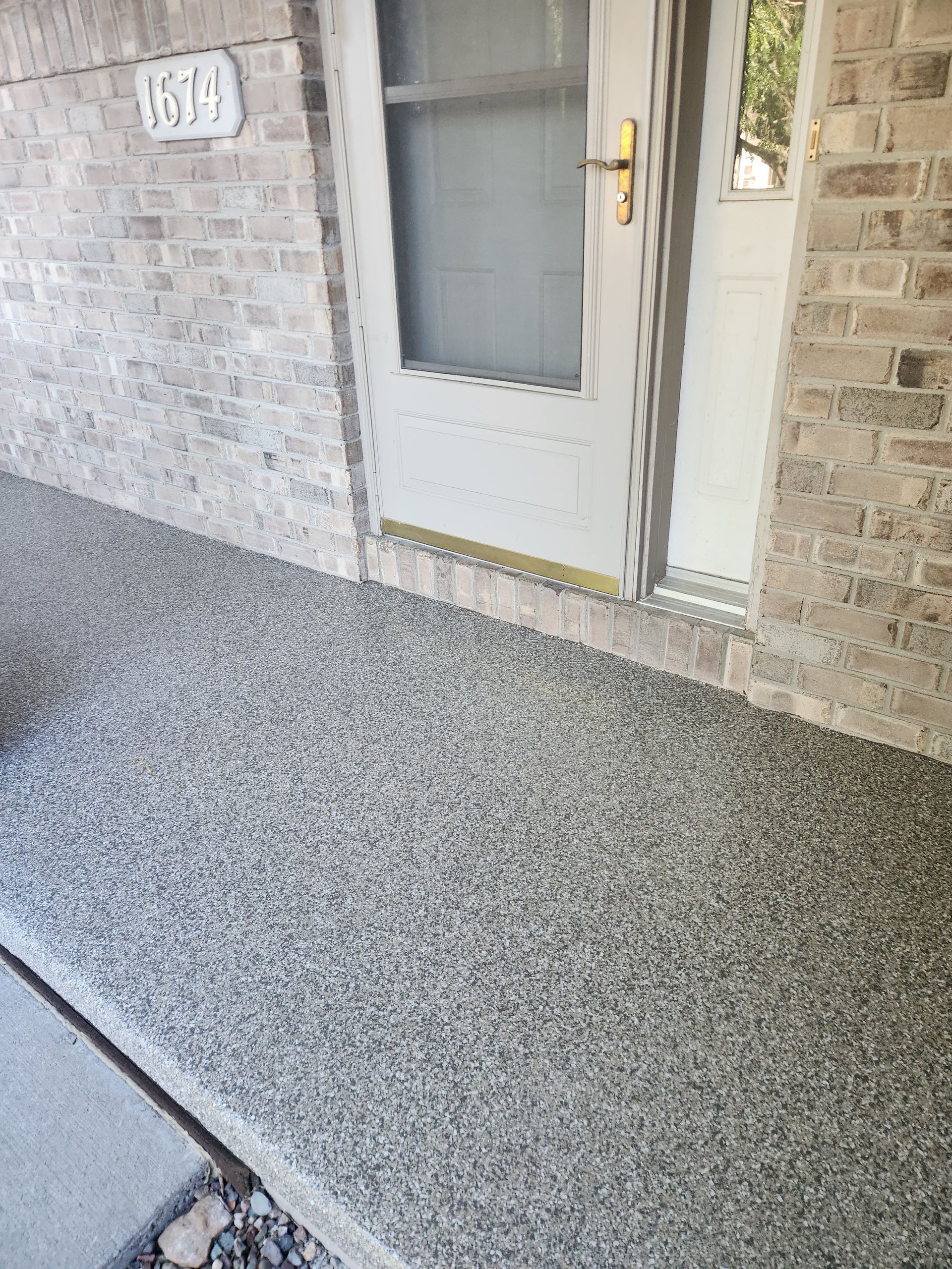 A concrete porch with a brick wall and a door.