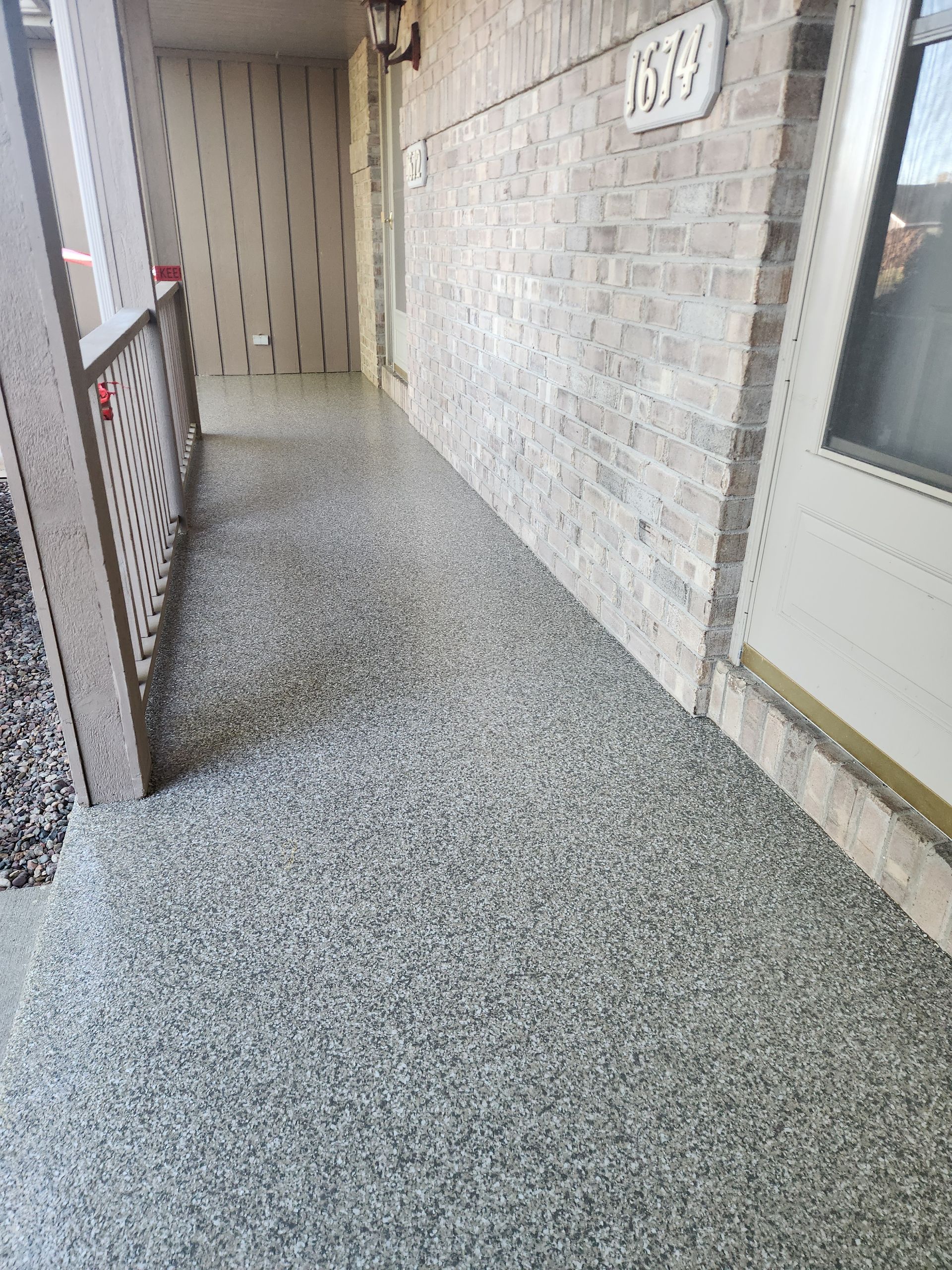 A hallway with a concrete floor and a brick wall.