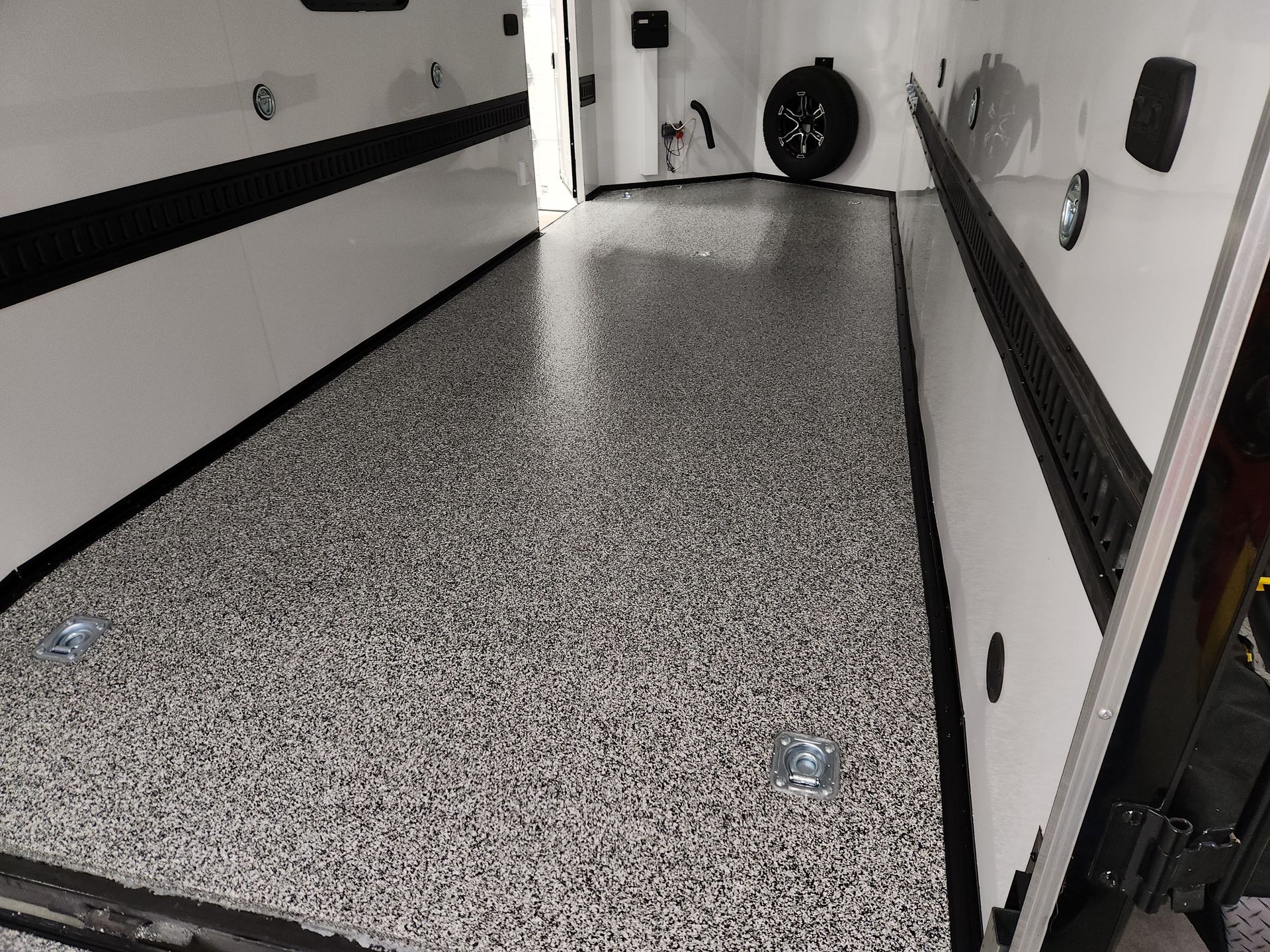 A garage with a gray and white floor and a tire on the wall.