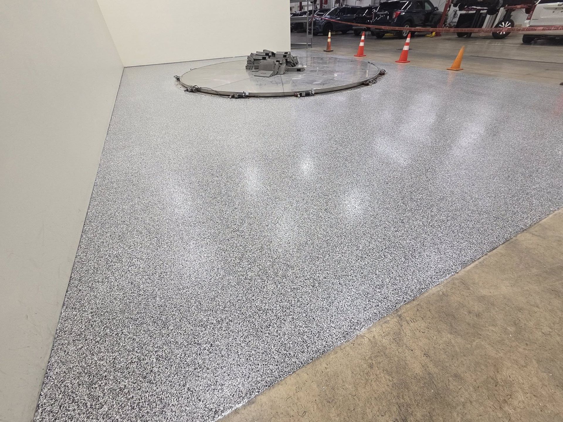 Epoxy-coated floor in a commercial space, gray with flecks, near a wall and a concrete border.