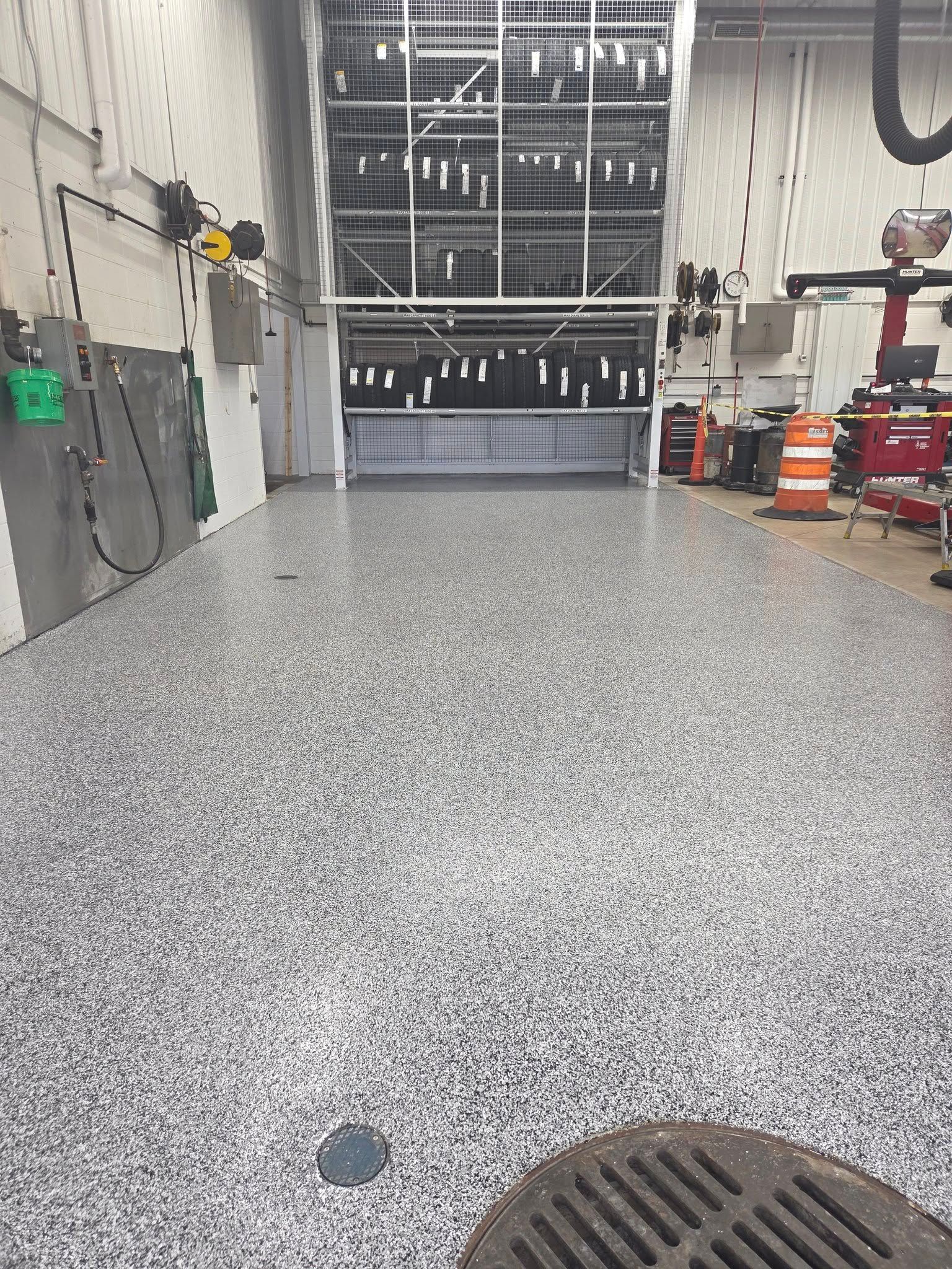 Garage interior with a speckled epoxy floor, open door, and equipment along walls.