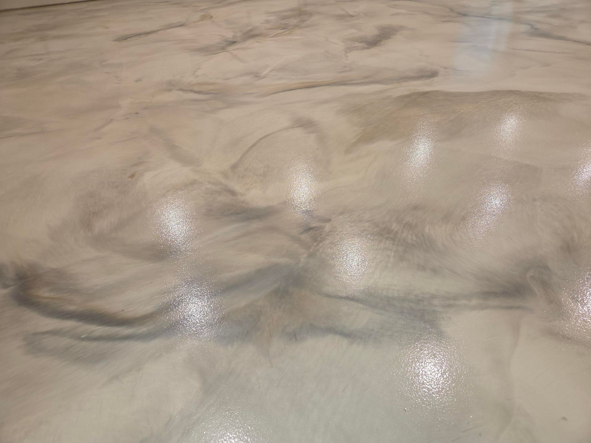 Glossy, light-colored floor featuring marbled, swirling patterns of white, gray, and silver tones