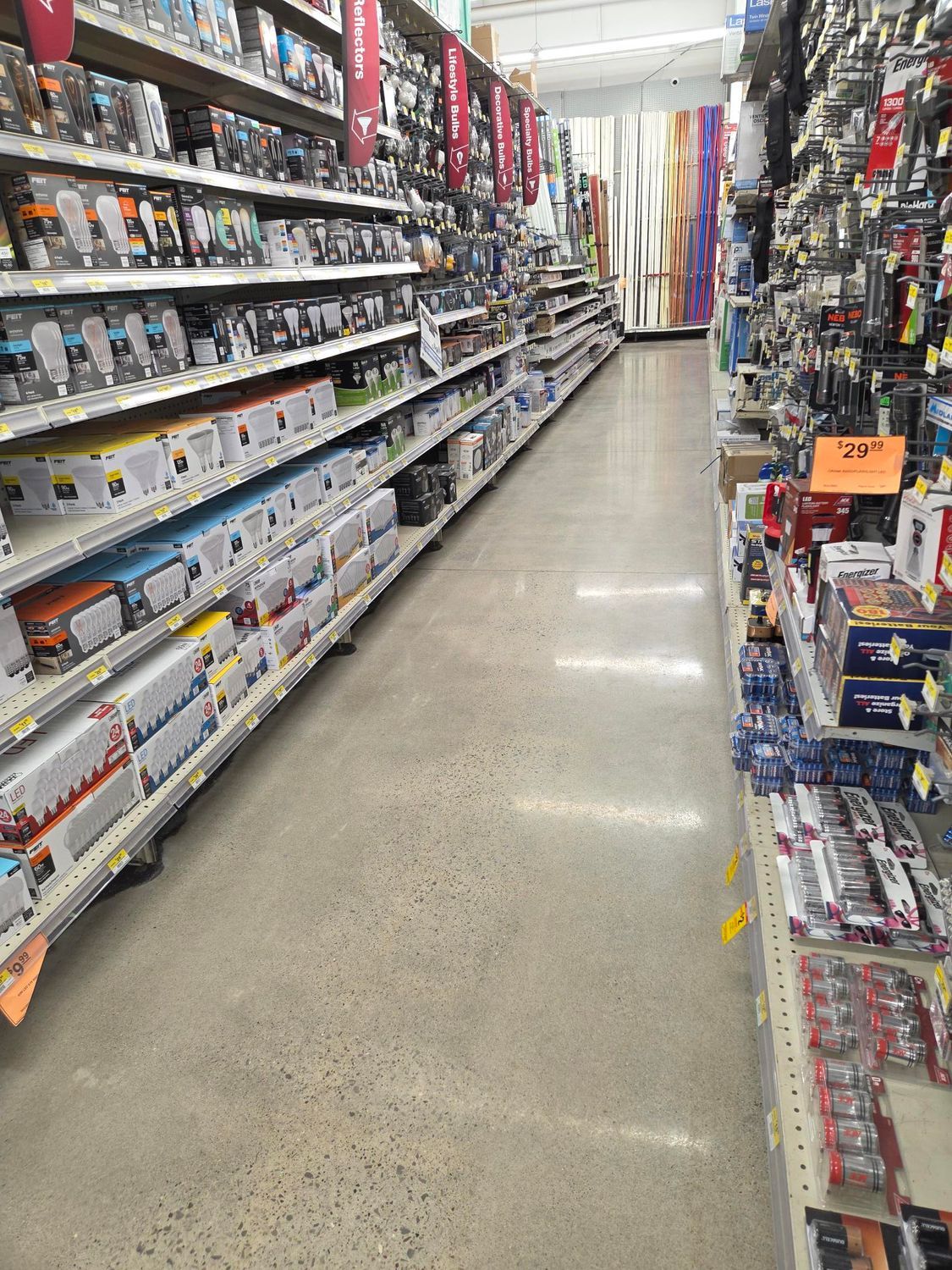 An aisle in a retail store with shelves packed with boxed merchandise on both sides and a polished concrete floor