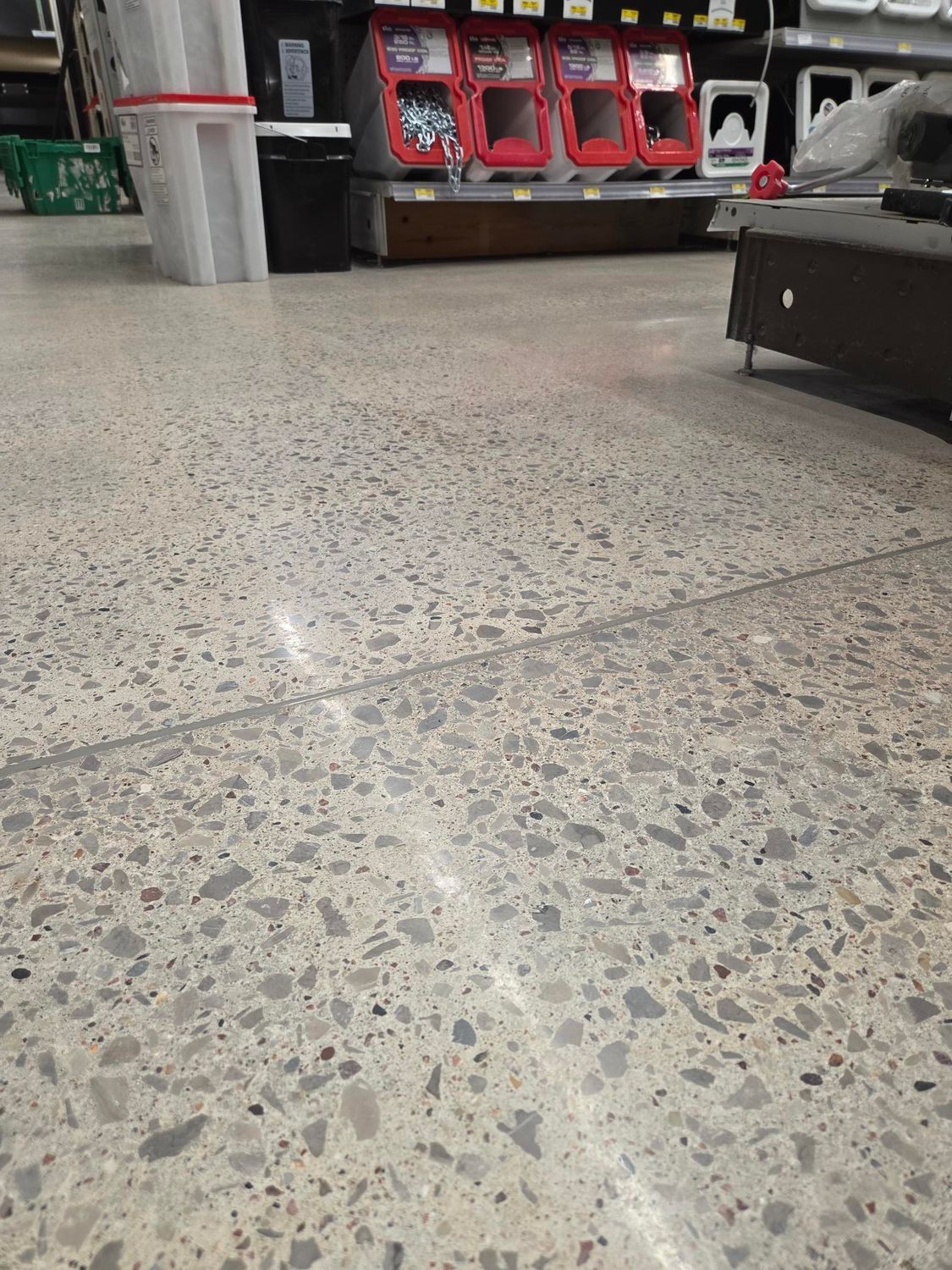 Speckled terrazzo floor in a public indoor space with red machines and seating in the background