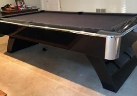 A set of seven translucent red polyhedral dice filled with gold flakes, arranged on a dark, textured surface.