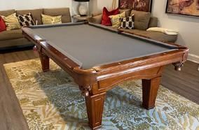 A set of seven translucent red polyhedral dice filled with gold flakes, arranged on a dark, textured surface.