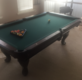 A set of seven translucent red polyhedral dice filled with gold flakes, arranged on a dark, textured surface.