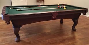 A set of seven translucent red polyhedral dice filled with gold flakes, arranged on a dark, textured surface.