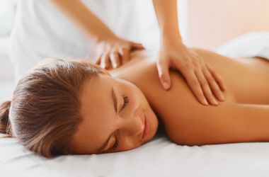 A woman is laying on a bed getting a massage.