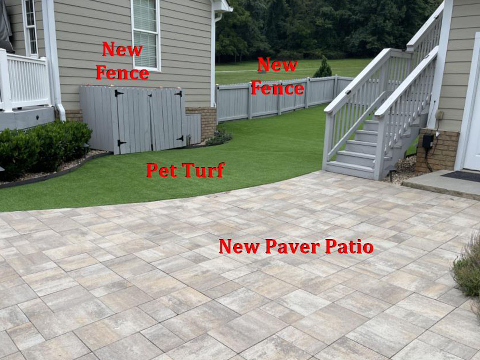 A new paver patio and pet turf yard with new gray fences and stairs next to a house.