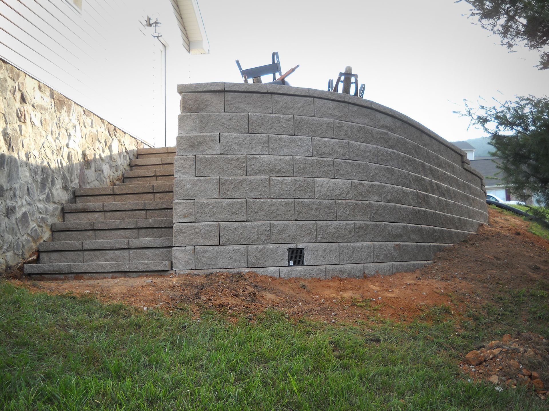 Stone retaining wall with steps leading up, next to house.