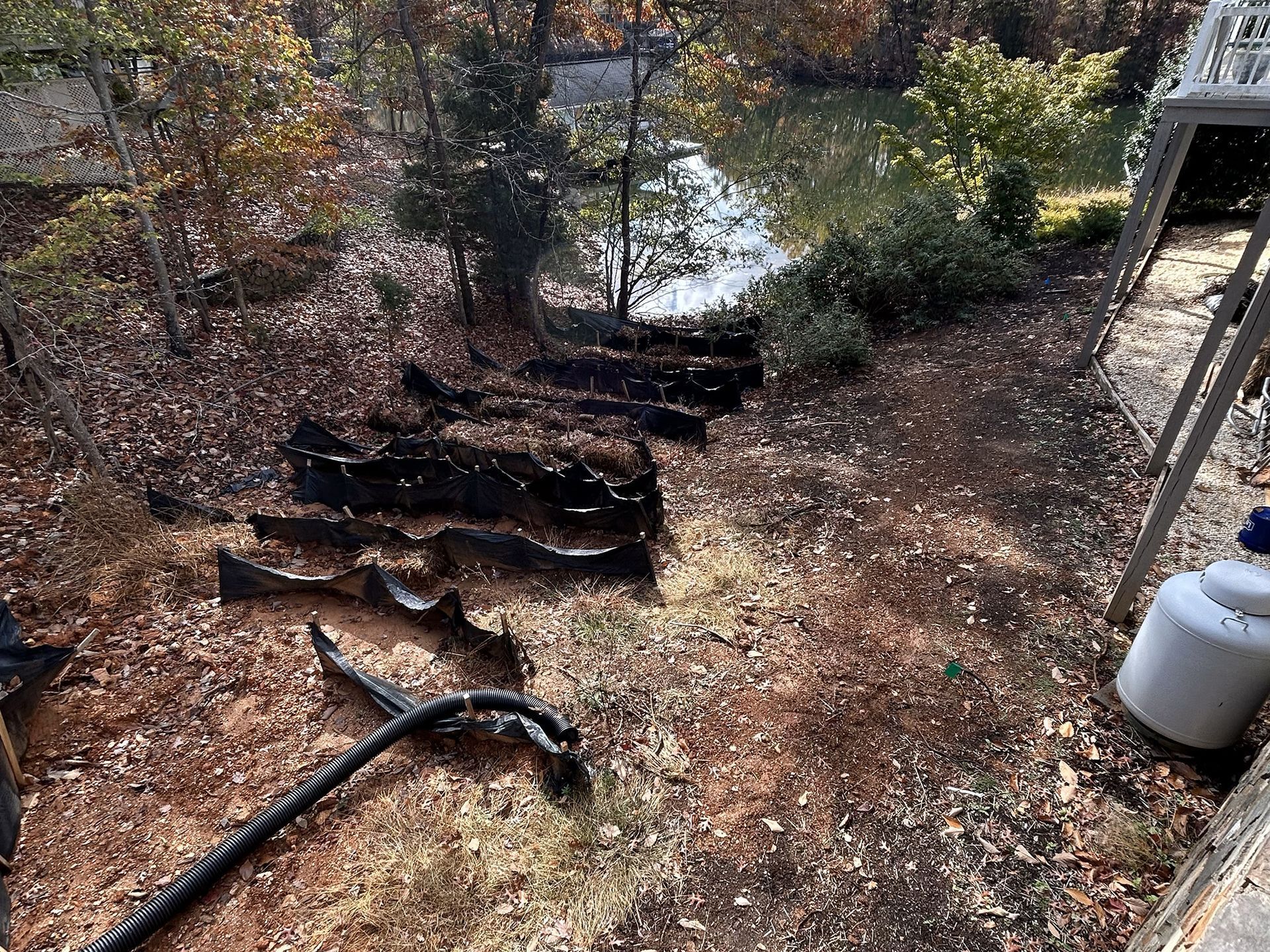 Staircase leading down to a lake, surrounded by brown leaves and foliage. A propane tank is in the foreground.