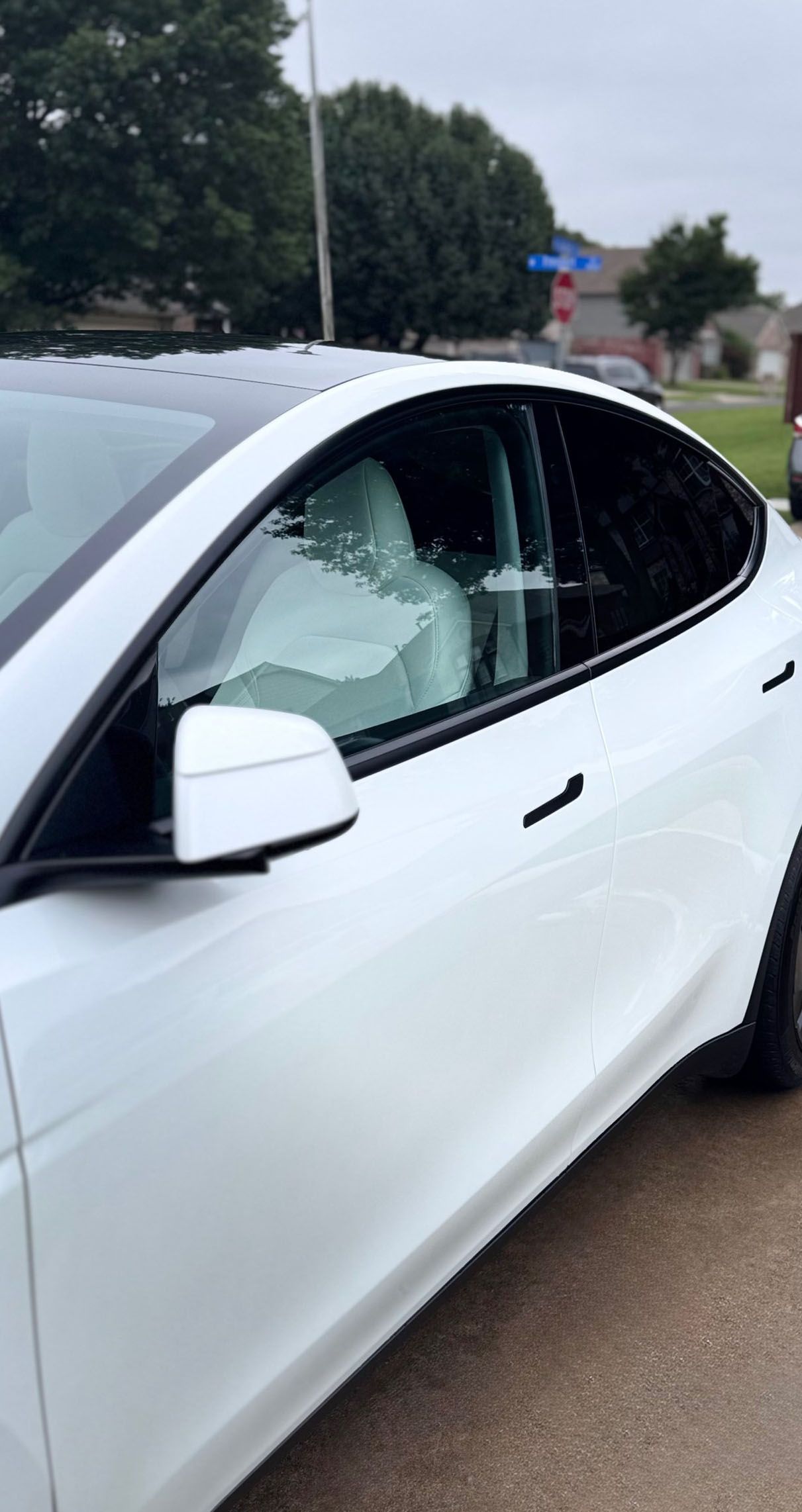 White Tesla car parked outdoors with tinted windows.