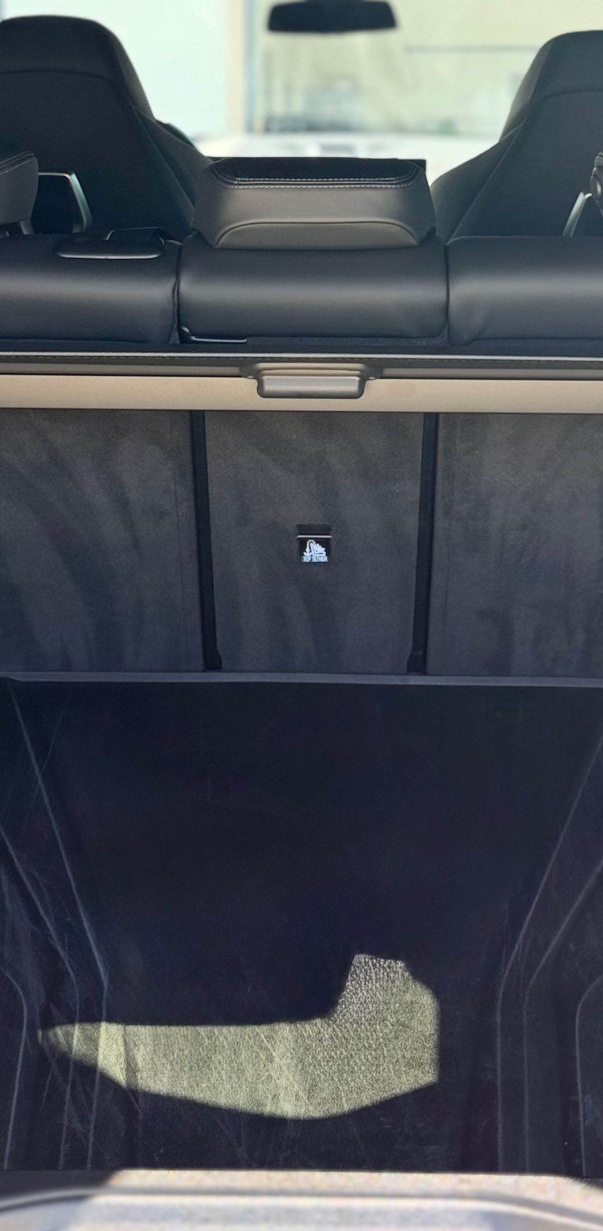 Interior view of a car trunk with black seats, a cargo cover, and a dark storage area.