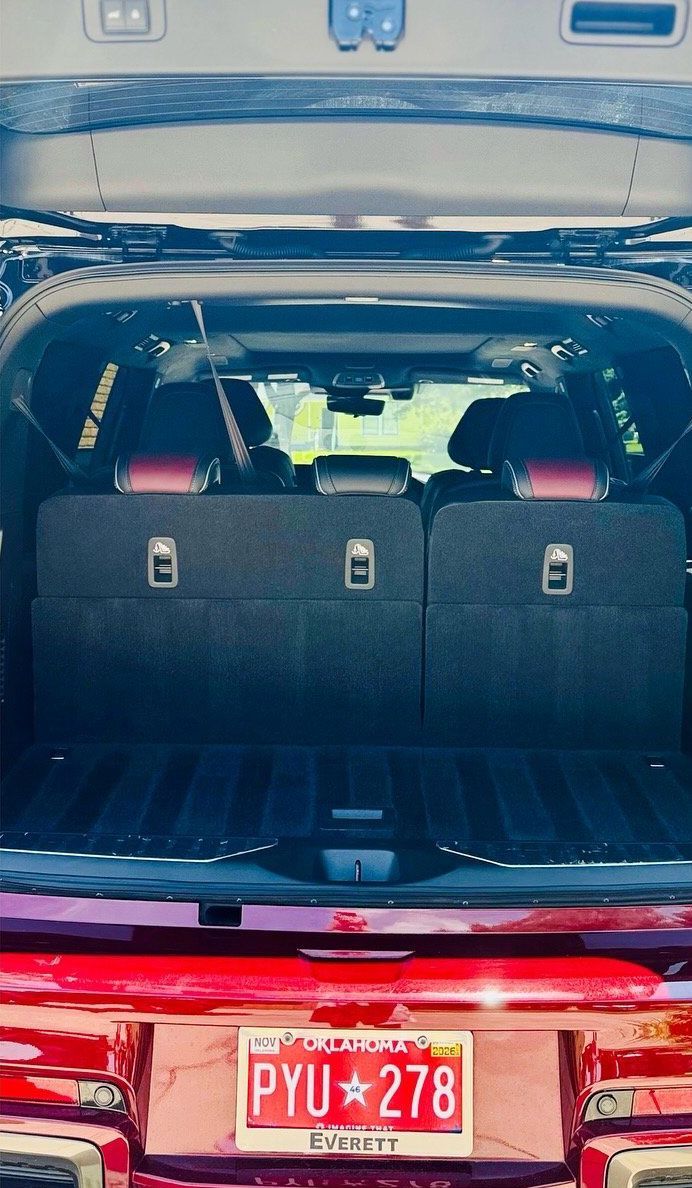 Red SUV cargo area with folded black seats and a license plate.
