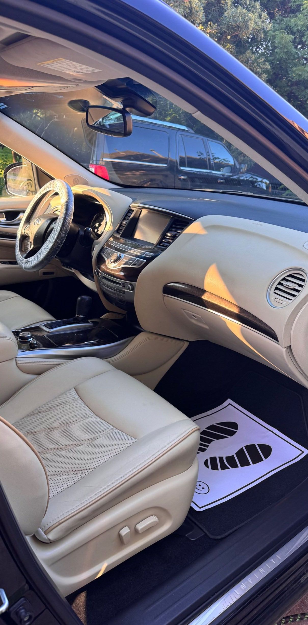 Interior of a beige car. The dashboard and front seats are visible, with a footstep-shaped floor mat.