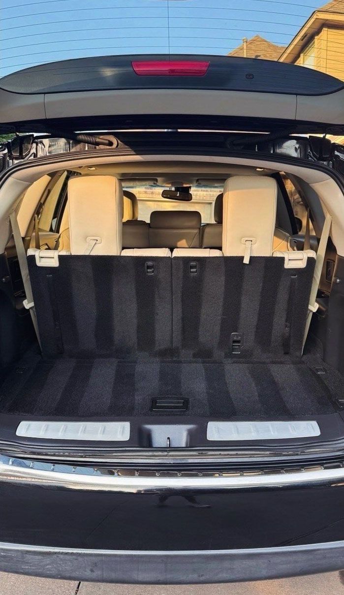Open trunk of a black SUV with beige interior, showing cargo space.