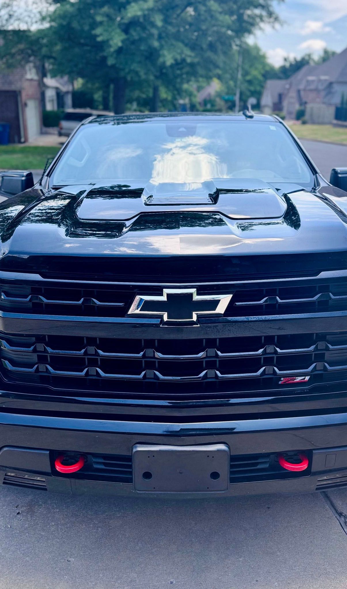 Black Chevrolet truck with red tow hooks, parked on a driveway.
