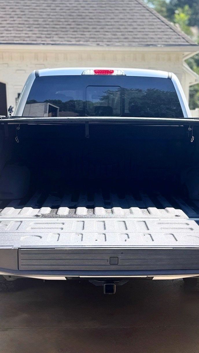 Open empty pickup truck bed, facing away. Black interior. Silver truck exterior.