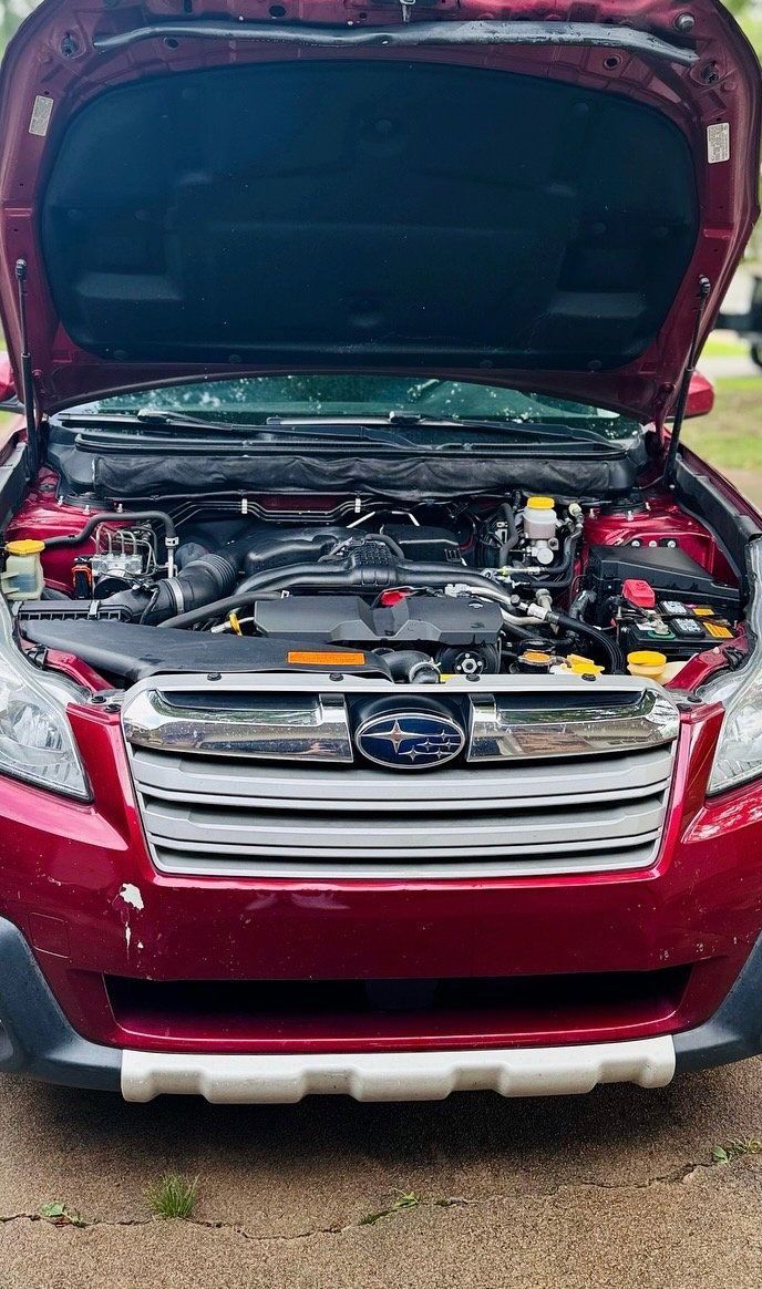 Red Subaru Outback with hood open, showing engine.