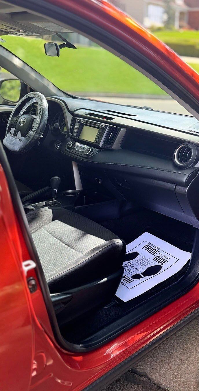 Interior view of a red Toyota RAV4 with black and gray seats, open door.