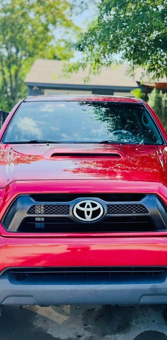 Red Toyota Tacoma truck parked in front of a house.