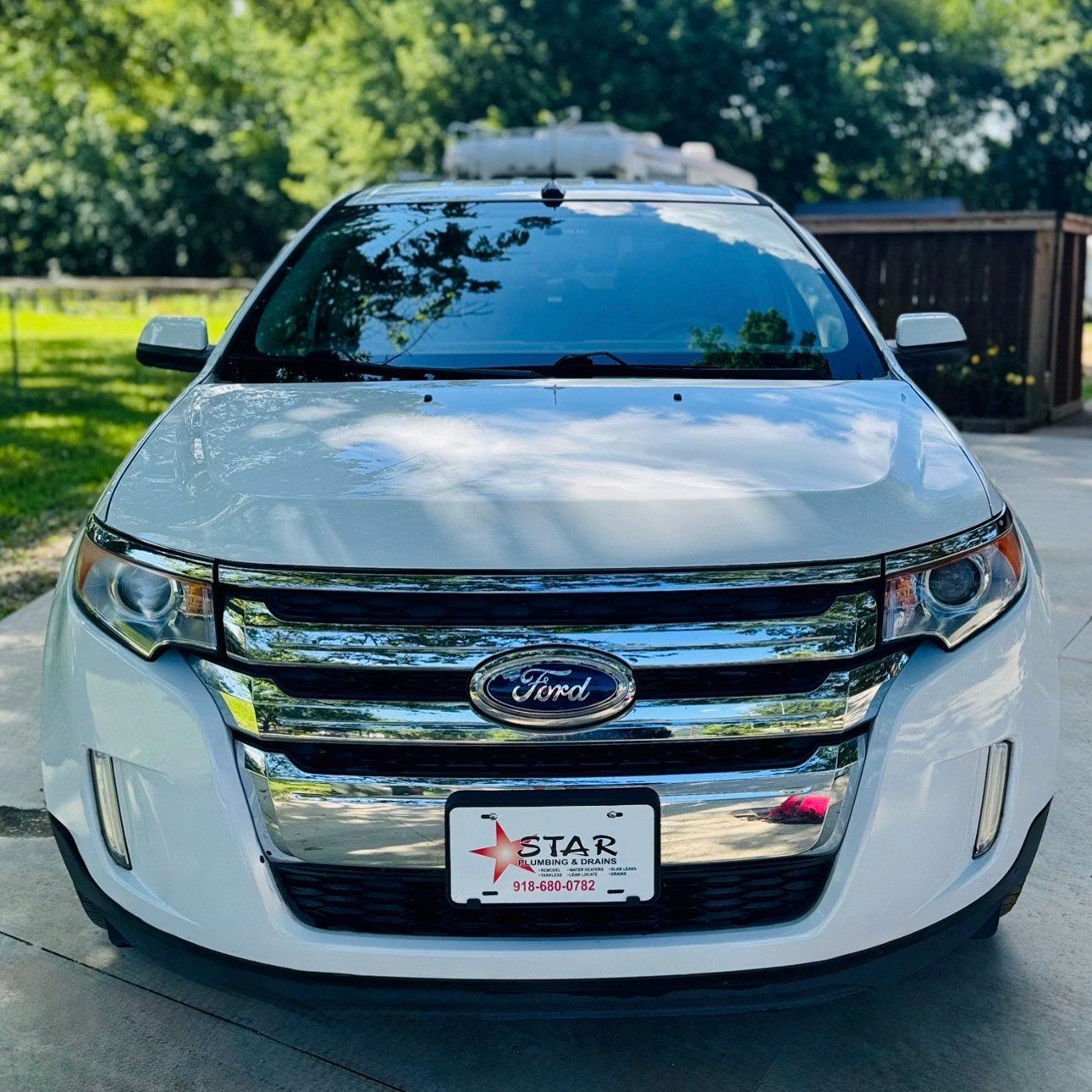 White Ford Edge, front view, chrome grill, Star license plate, parked outdoors.