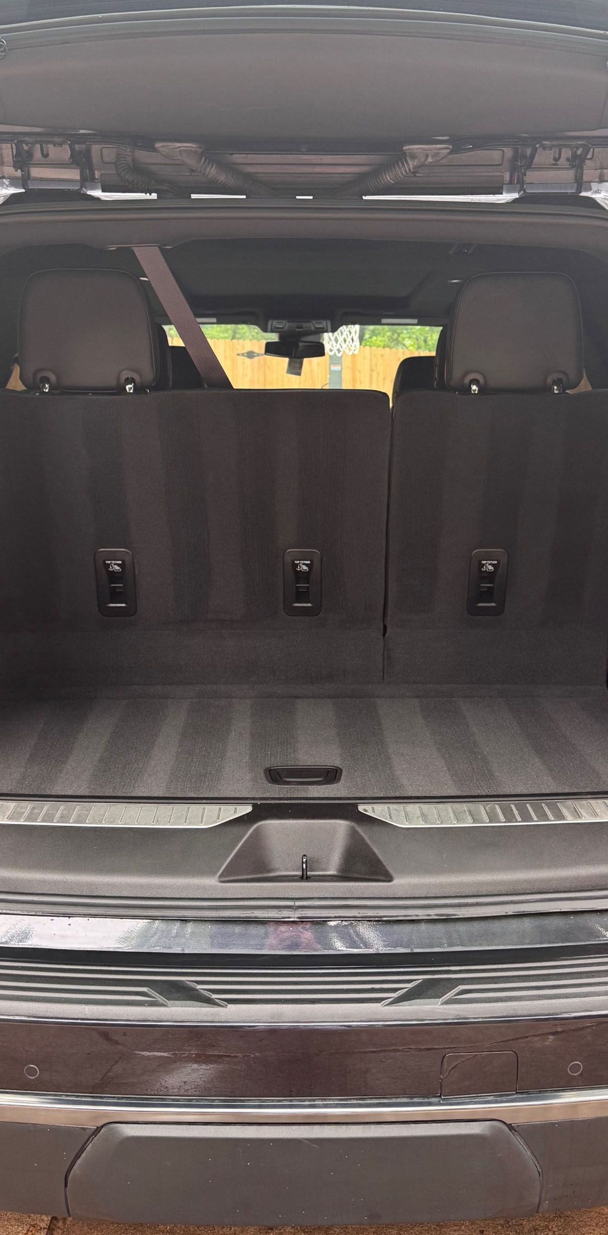The open trunk of a dark SUV, showing the back seats and cargo area with striped fabric.