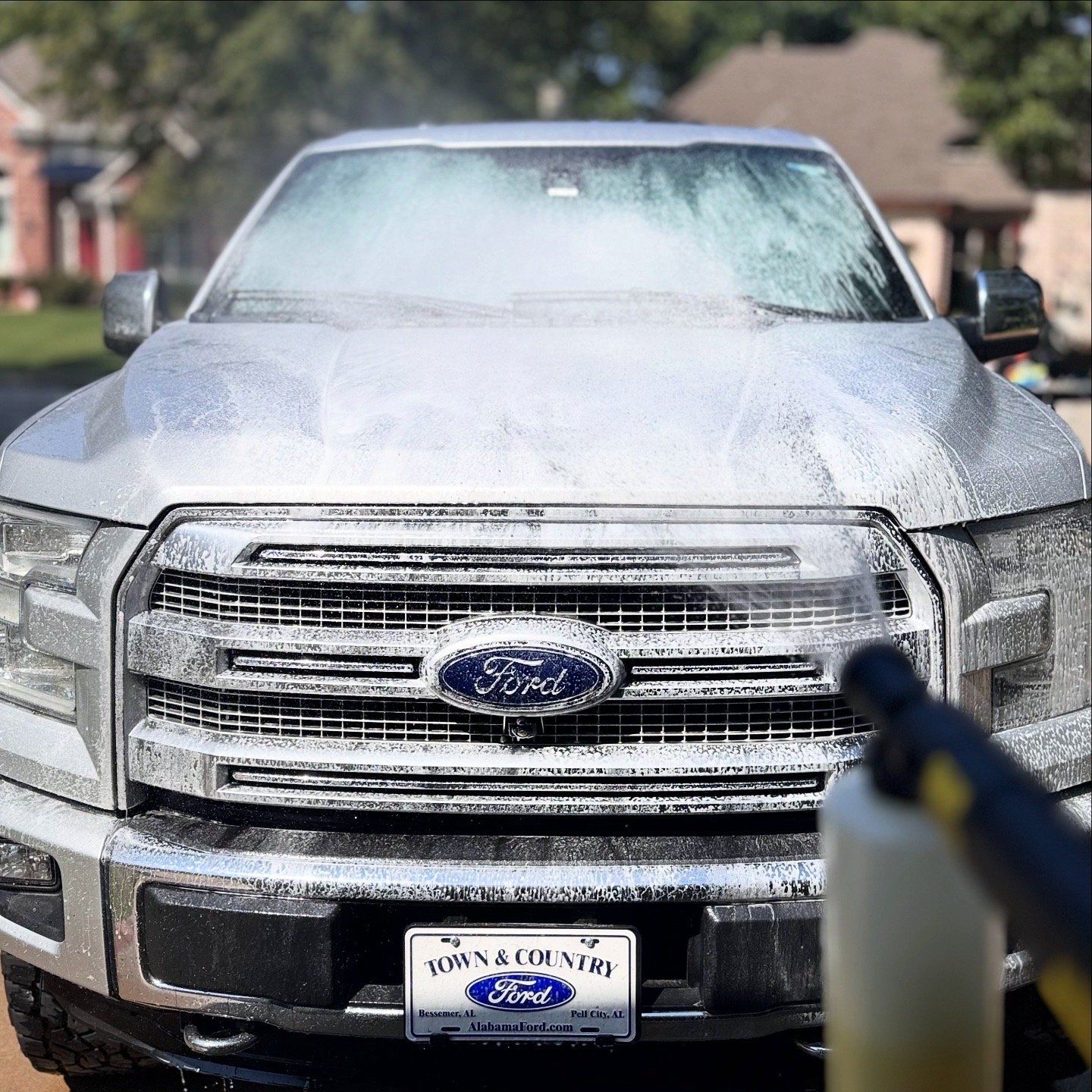 Silver Ford pickup truck covered in soap, being washed outdoors.